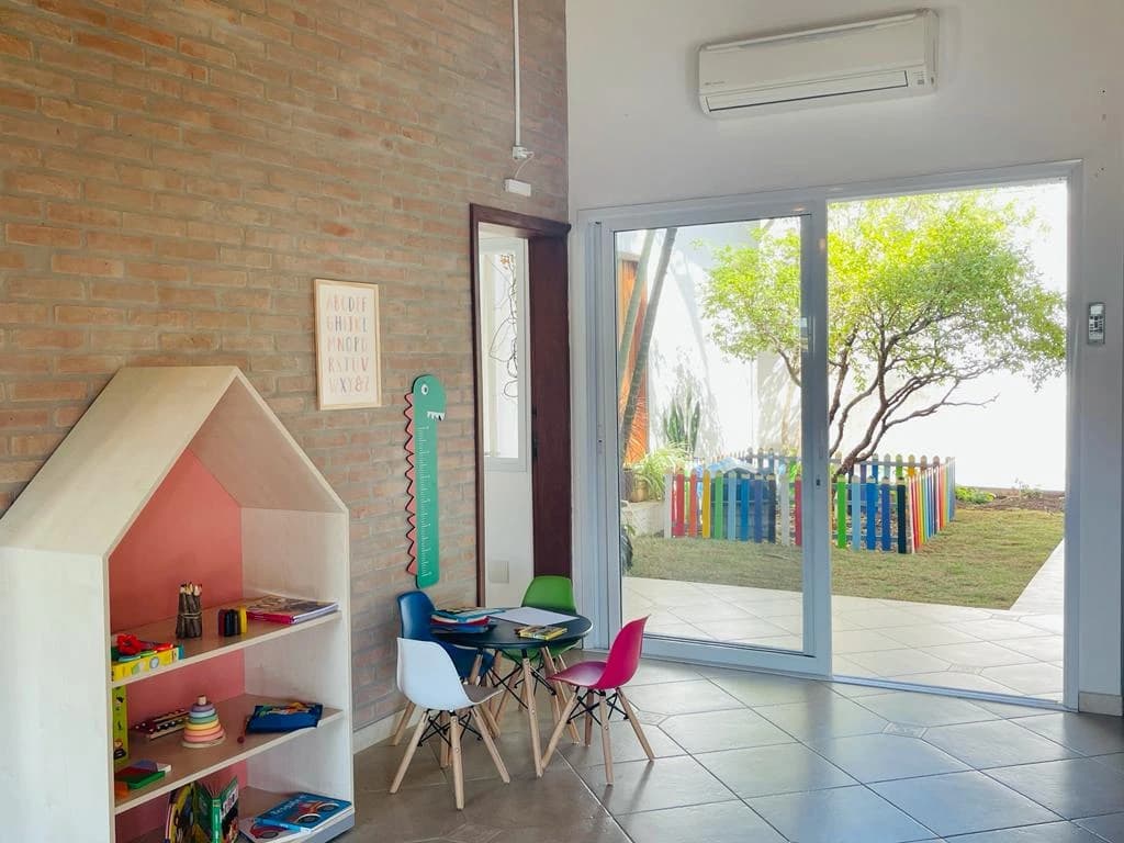 Sala com estante em formato de casinha e vista para o jardim